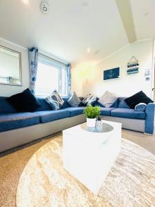 a living room with a blue couch and a white table at Ocean Breeze in Filey +98 photos