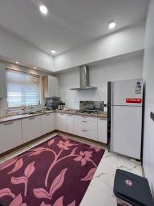 a kitchen with white cabinets and a pink rug at السكن المثالي - alsakan almithaliu in Abha