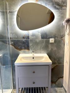 Un baño con un lavabo blanco y un espejo. en Onyx Blue, en Saint-Aignan