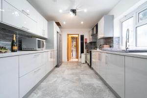 una cucina con armadietti bianchi e forno a microonde di Large 7 Bedroom Townhouse with Parking - WIFI & Netflix - Sleeps 16 - 568P a Birmingham
