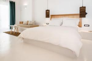 een witte slaapkamer met een groot bed en een bank bij Piccole Case in Kamari