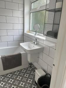 a white bathroom with a sink and a mirror at Sea Song Cottage in Broadstairs