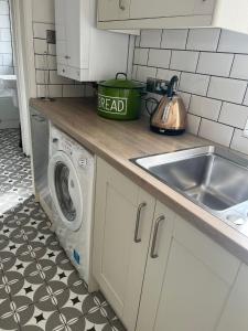 a kitchen with a sink and a washing machine at Sea Song Cottage in Broadstairs