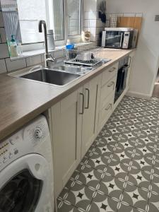 a kitchen with a sink and a washing machine at Sea Song Cottage in Broadstairs