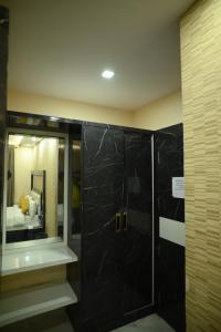 een badkamer met een douche, een wastafel en een spiegel bij Kings Inn Hotel in Rānchī