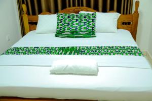 un letto con lenzuola e cuscini verdi e bianchi di Macchiato Suites a Kigali