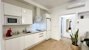a white kitchen with a sink and a microwave at SIBS Sanlúcar Guadalquivir 2 Coqueto Ideal Parejas in Sanlúcar de Barrameda +18 photos
