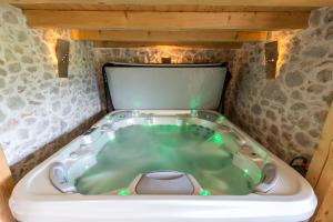 uma banheira de hidromassagem num quarto com uma parede de pedra em La Ferme Francej Luxury Farmhouse Bohinj em Bohinjska Bistrica