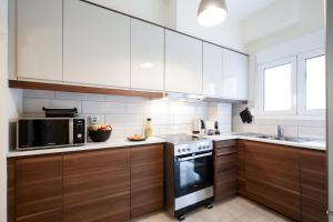a kitchen with white cabinets and a microwave and a stove at Cozy 3 Bedroom Retreat next to Kolonaki - Greecing in Athens