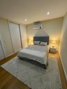 a bedroom with a bed and two lamps and a rug at Penthouse com Jacuzzi in Coimbra