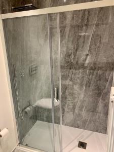 een douche met een glazen deur in de badkamer bij AJ Lux Apartments in Catania
