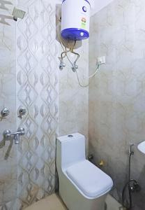 a bathroom with a white toilet and a blue bucket at Hotel In Lajpat Nagar in New Delhi