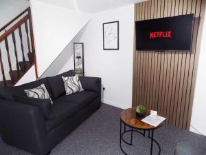 a living room with a black couch and a table at Modern 3 Bed - Lincoln - Parking in Lincoln