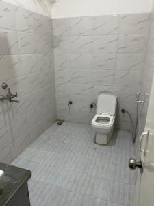 a white bathroom with a toilet and a sink at Zoravar Farms in Sohna