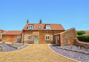 a brick house with a cobblestone driveway at Top End Cottage 6 in Ringstead