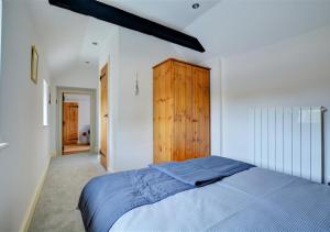 um quarto com uma cama azul e um armário de madeira em Top End Cottage 6 em Ringstead