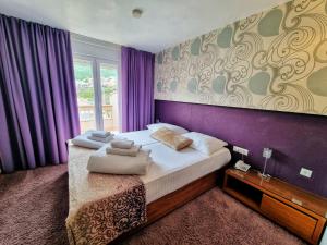 1 dormitorio con 1 cama grande y paredes moradas en Hotel Gala Split, en Podstrana
