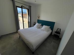 a bedroom with a white bed and a large window at CLOS ARIA NOVA in Lucciana