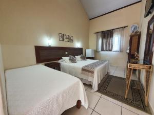 a hotel room with two beds and a window at Pousada Ventos de Outono in São Roque