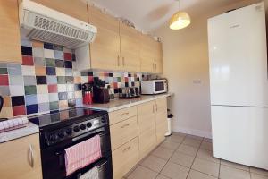 una cocina con estufa y refrigerador en CAE GRUGOG COTTAGE-3 Bed-Sleeps 6-Ground Floor Bathroom, en Trearddur