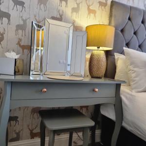a bed with a desk with a lamp and a bedside table at Rose Villa in Oban