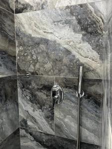 y baño con ducha y pared de piedra. en Villa Galaxy Santorini en Fira