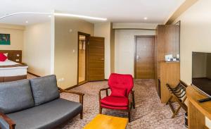 une chambre d'hôtel avec un canapé et un fauteuil rouge dans l'établissement Red Rock Resort, à Oulan-Bator