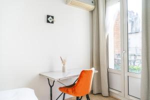 escritorio con silla naranja en una habitación con ventana en Résidence Courcelle, en Levallois-Perret