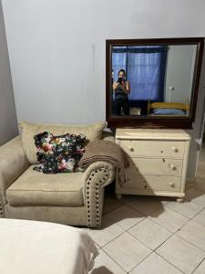 una mujer tomando una foto de un sofá y un tocador con un espejo en Liliana, en Capiatá