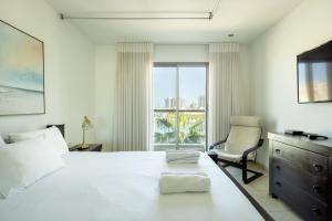 1 dormitorio con 1 cama, 1 silla y 1 ventana en Marina Waterfront Haven by Sea N' Rent, en Herzelia 