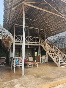 een hut met een trap, een bank en een tafel bij Sunset Getaway- Villa Makuti in Kizimkazi
