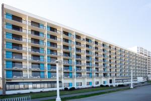 The Barclay Towers Hotel and Resort في فرجينيا بيتش: مبنى شقة بيضاء كبيرة مع نوافذ زرقاء
