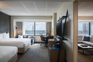トレドにあるRenaissance Toledo Downtown Hotelのベッド2台、ソファ、テレビが備わるホテルルームです。