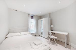 una camera bianca con letto e scrivania di Modern 3 Bed Apartment in Hampstead a Londra