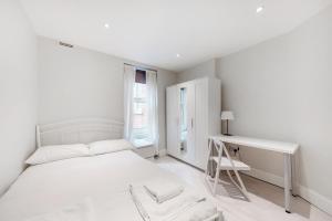 a white bedroom with a bed and a desk at Modern 3 Bed Apartment in Hampstead in London