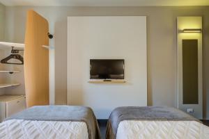 a room with two beds and a tv on the wall at Rio hotel by Bourbon Indaiatuba Viracopos in Indaiatuba
