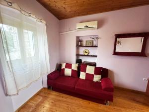 ein rotes Sofa im Wohnzimmer mit Fenster in der Unterkunft Tolis House in Korfu-Stadt