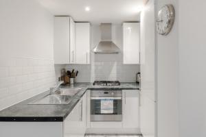 a white kitchen with a sink and a stove at Park view / Baker Street / Marylebone Apartments in London