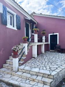 różowy dom ze schodami i kwiatami przed nim w obiekcie Tolis House w Korfu