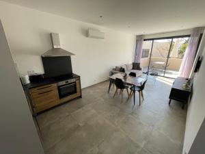 a living room with a kitchen and a table with chairs at CLOS ARIA NOVA in Lucciana