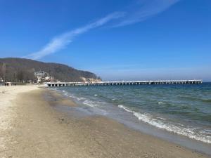 una playa de arena con un muelle en el agua en Villa Orłowska Apartamenty, en Gdynia