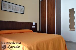 Hospedería Laredo في لا كارلوتا: غرفة نوم مع سرير وبطانية برتقالية