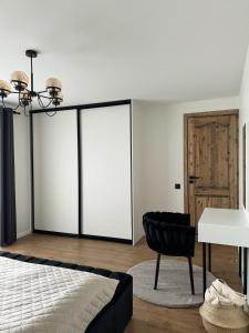 a bedroom with a bed and a black chair at Sea Oasis apartment in Liepāja