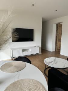 a living room with two tables and a flat screen tv at Sea Oasis apartment in Liepāja