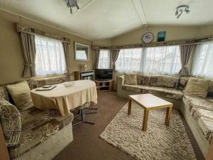 ein Wohnzimmer mit einem Sofa und einem Tisch in der Unterkunft Great Caravan At Breydon Water Holiday Park, Ref 10086b in Belton