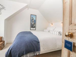 een slaapkamer met een wit bed met een blauwe deken erop bij Topsail in Dartmouth