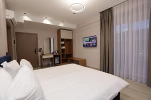 a bedroom with a white bed and a television at Residence Inn Hotel in Tirana
