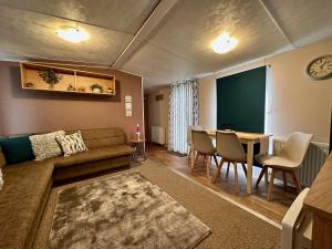 a living room with a couch and a table at Great Caravan With Wifi And Decking At Dovercourt Holiday Park Ref 44006c in Great Oakley