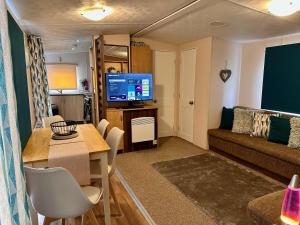 a living room with a couch and a table at Great Caravan With Wifi And Decking At Dovercourt Holiday Park Ref 44006c in Great Oakley