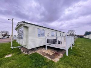 a small white house sitting on a grass field at Lovely Caravan With Decking And Free Wifi At Valley Farm, Essex Ref 46610v in Great Clacton